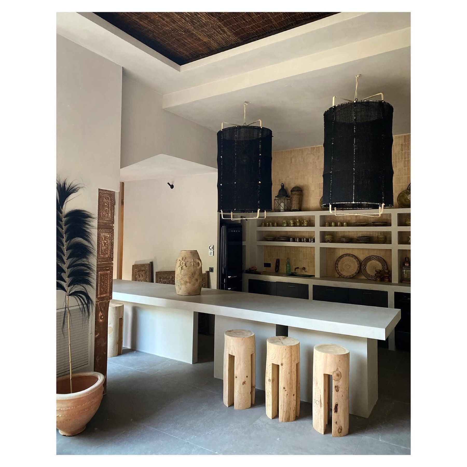 Cuisine et grande table en béton ciré, tabourets en rondins de bois — Casa Jungle