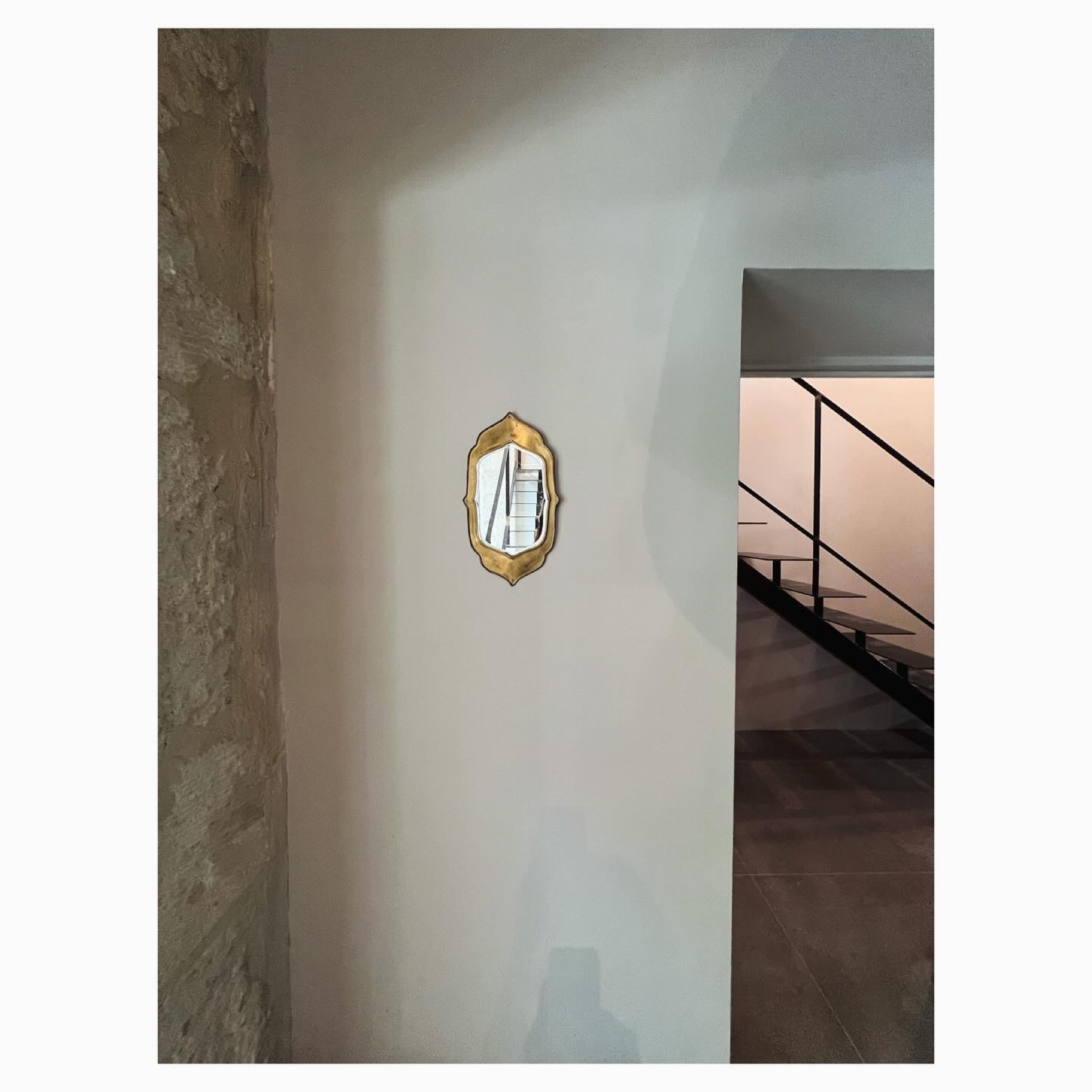Détail : miroir doré sur mur de chaux, escalier acier — Casa Jungle
