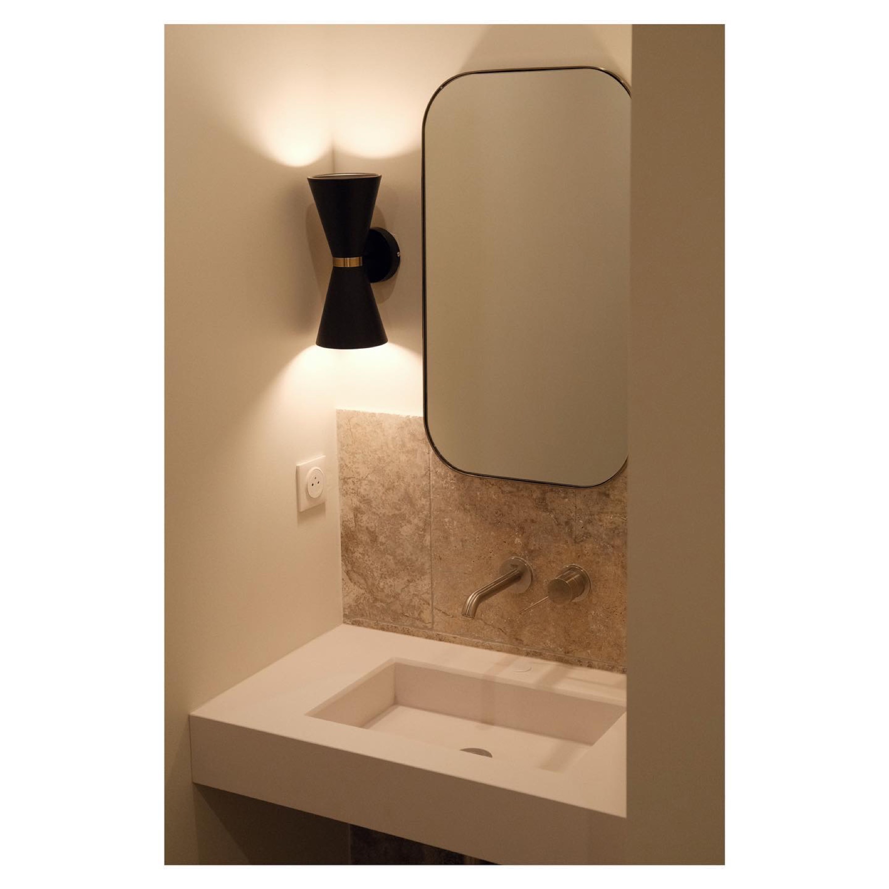 Salle d'eau en travertin, vasque solid-surface et applique noire — Pont Juvénal